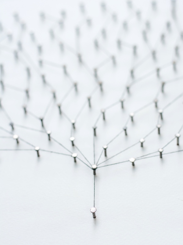 nails in white paper with string simulating a network.